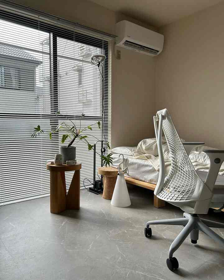 ベージュとホワイトのトーンの寝室、木製サイドテーブルと植物が配置されたミニマルな空間