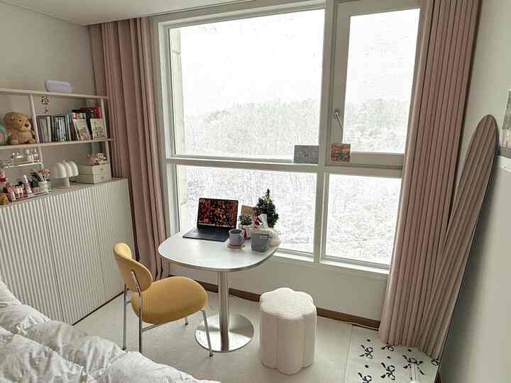 白を基調としたコンパクトな寝室、マスタード色の椅子と全身鏡、ラグが配置された雰囲気のあるインテリア