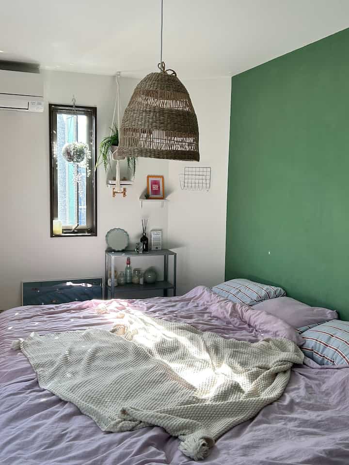 White and green bedroom featuring a woven pendant light and pastel duvet cover creating a cozy atmosphere
