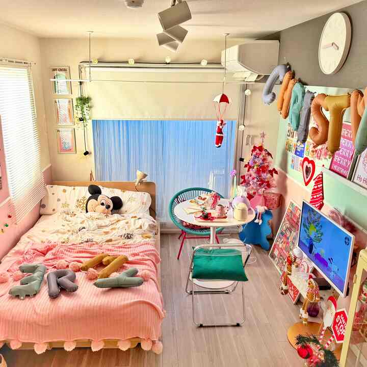 ピンクとホワイトの色調の寝室、ベッドと丸いダイニングテーブル、クリスマス装飾が配置された雰囲気あるインテリア