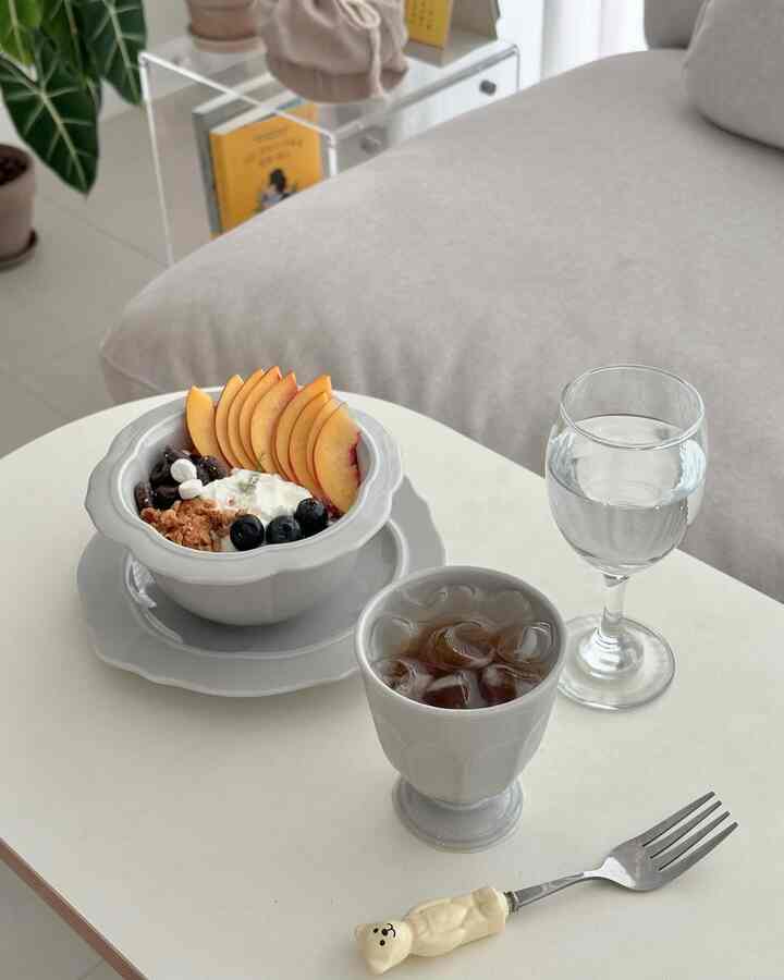 明るいホワイトトーンのホームカフェ空間、白いテーブルにフルーツとヨーグルト、アイスドリンクが置かれた清潔なテーブル