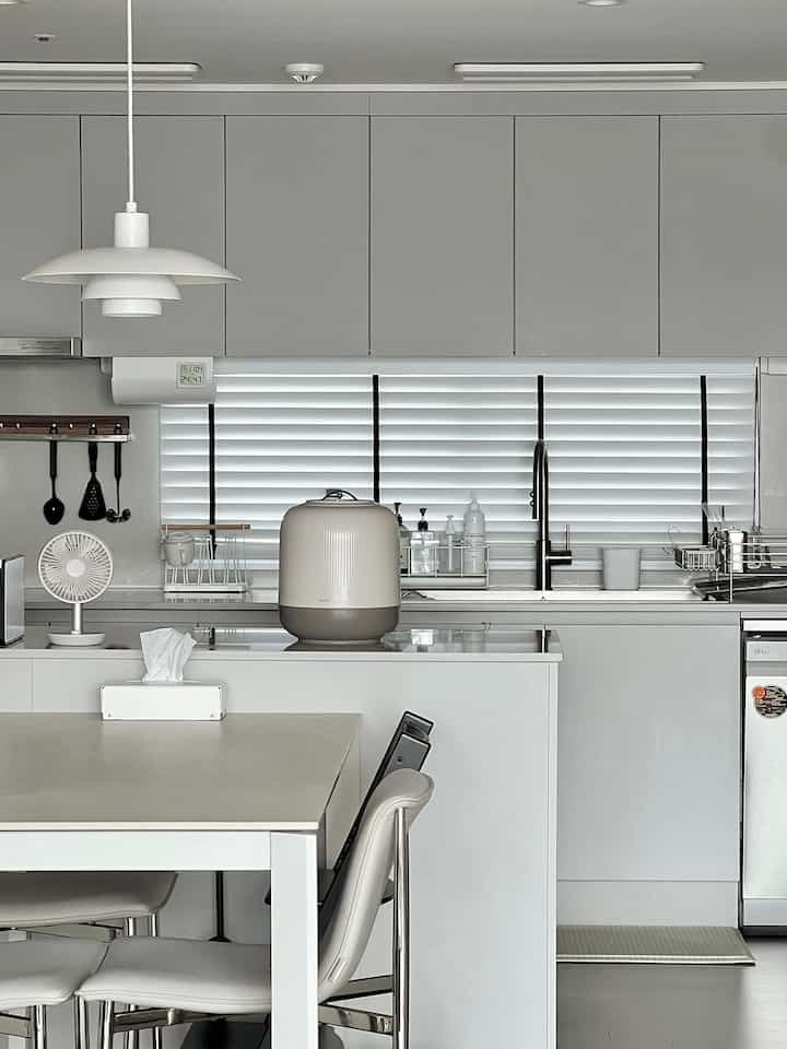 White and gray toned kitchen space featuring a vacuum rice container and dining table in a clean modern interior