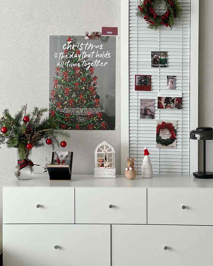 白と赤の色調のリビングルームチェストにクリスマスポスター、絵はがき、装飾品が配置された暖かみのある雰囲気のインテリア