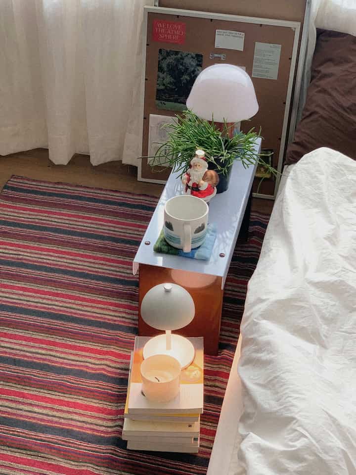 白と茶色のトーンの寝室、ストライプのラグとプランターとサンタのオブジェが置かれた雰囲気のある空間