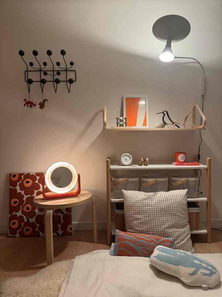Natural tone wood furniture and white walls create a cozy bedroom space featuring cushions and warm lighting elements.