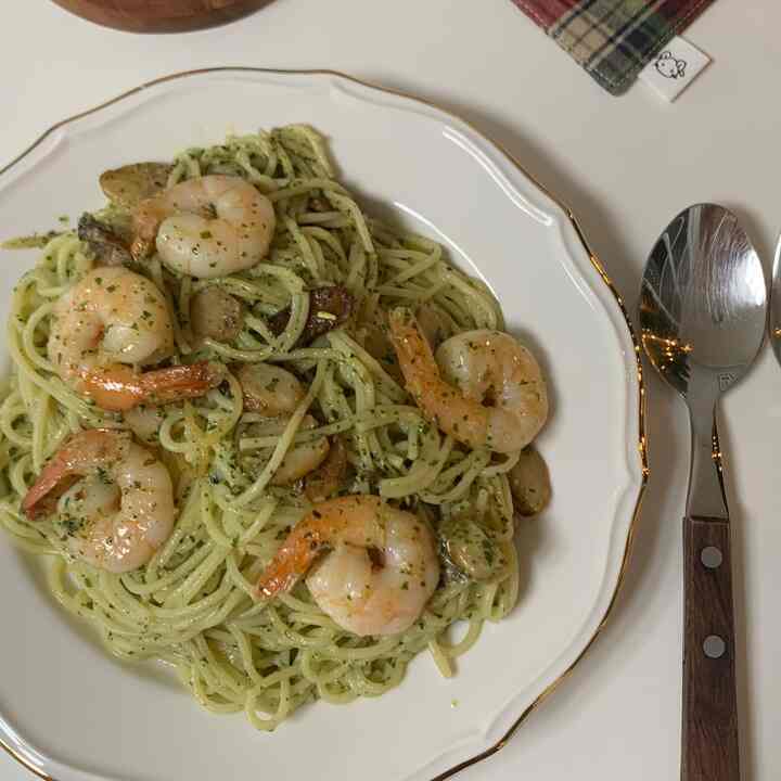 ゴールドラインのある白いヴィンテージ皿にエビとキノコのパスタ料理が乗った食卓