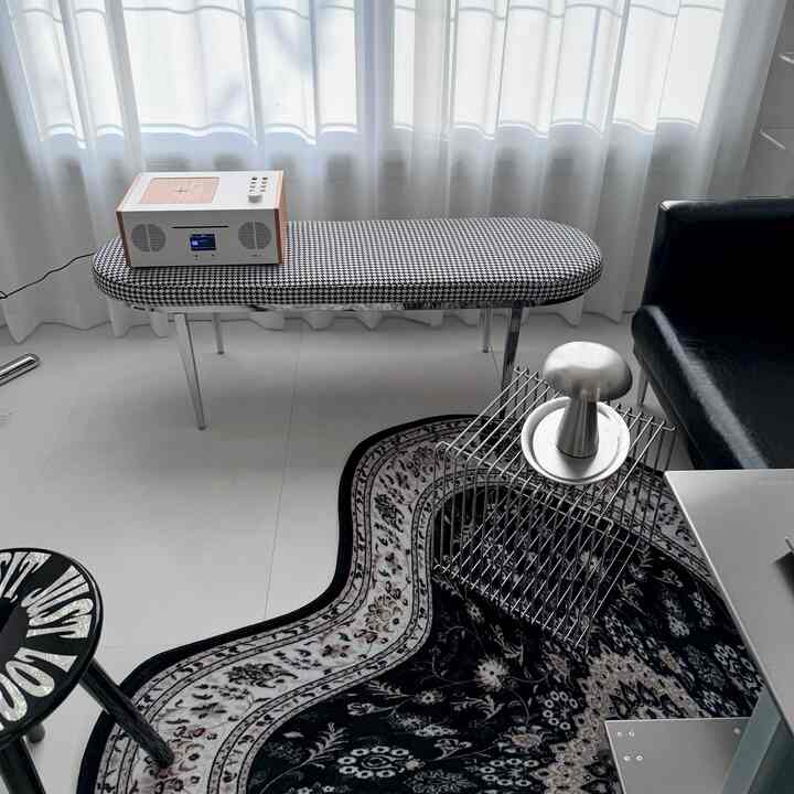 A white and black entrance space featuring a houndstooth patterned Mid-Century Modern stool and metallic objet for a chic look