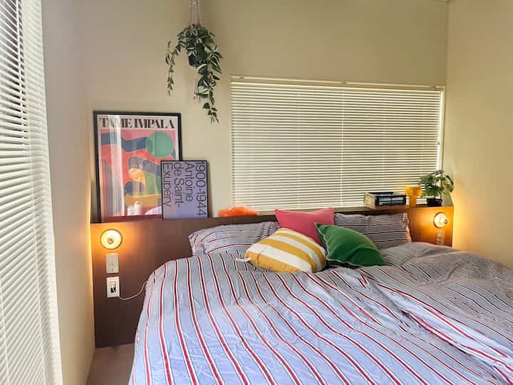 White and wood tone bedroom featuring striped bedding and colorful cushions creating a cozy atmosphere