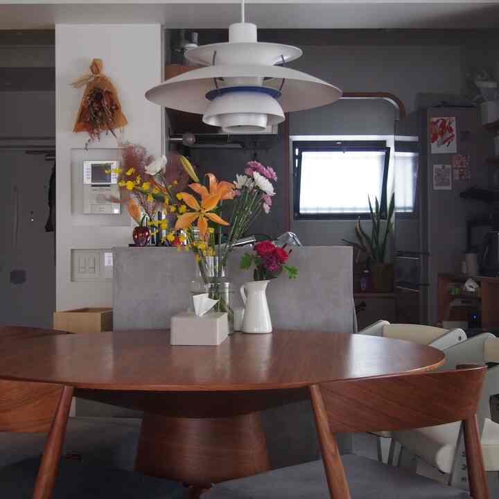 ブラウンの木製ダイニングテーブルと椅子が中央にあり、白いペンダントライトが吊るされたミッドセンチュリーモダンなダイニングルーム