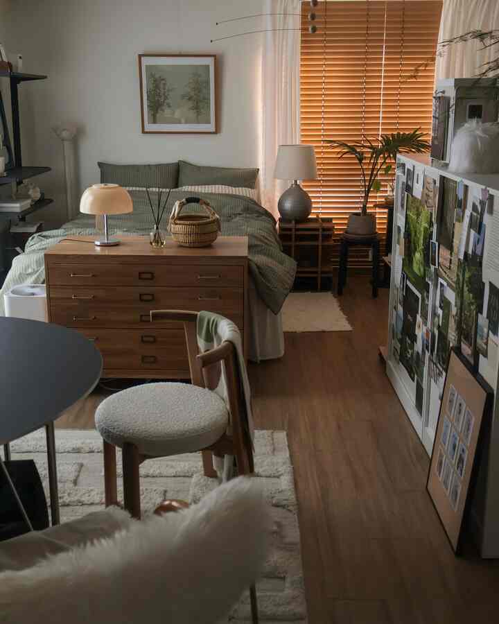 木目調と緑色のワンルーム寝室、ベッドと木製家具が配置された落ち着いた雰囲気のインテリア