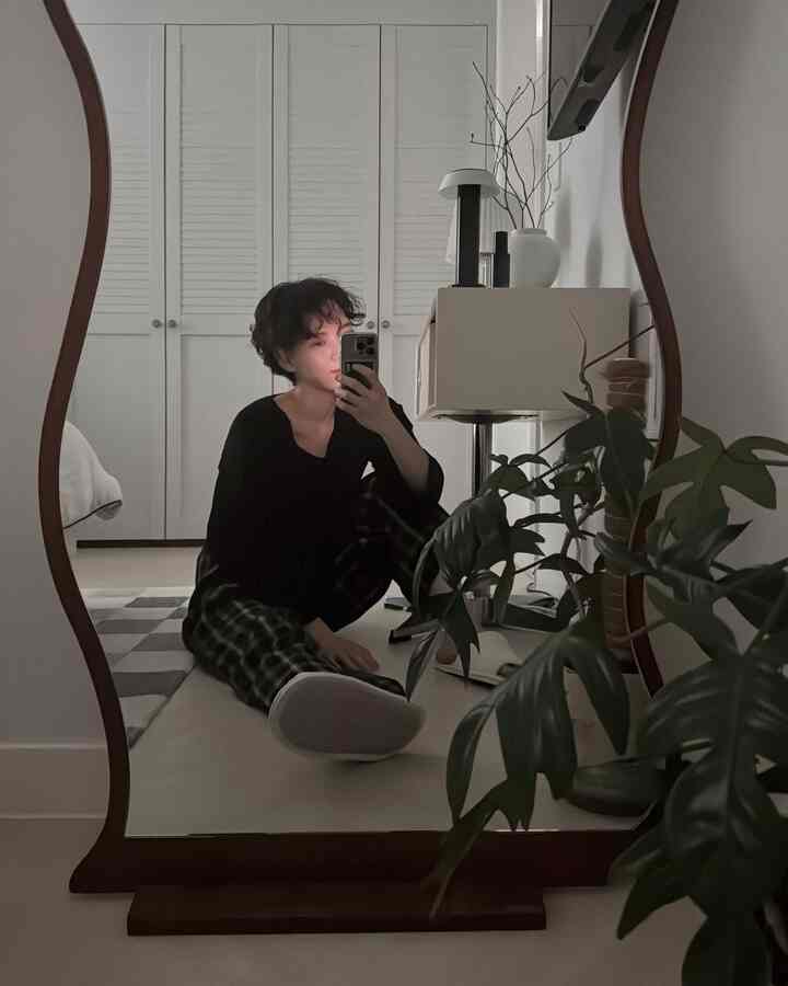 ホワイトの壁と木目調が調和した寝室、波型の木製全身鏡とコンソールテーブルが洗練された雰囲気を演出