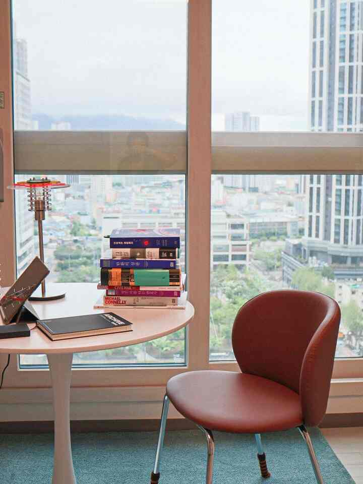 白と茶色のトーンの書斎、広い窓と机、茶色の椅子が配置された雰囲気のあるインテリア