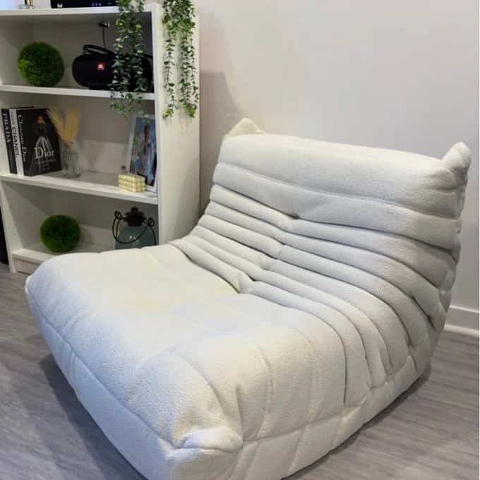 A modern white living room featuring a cozy bean bag lounge chair as the focal point in a minimalist interior