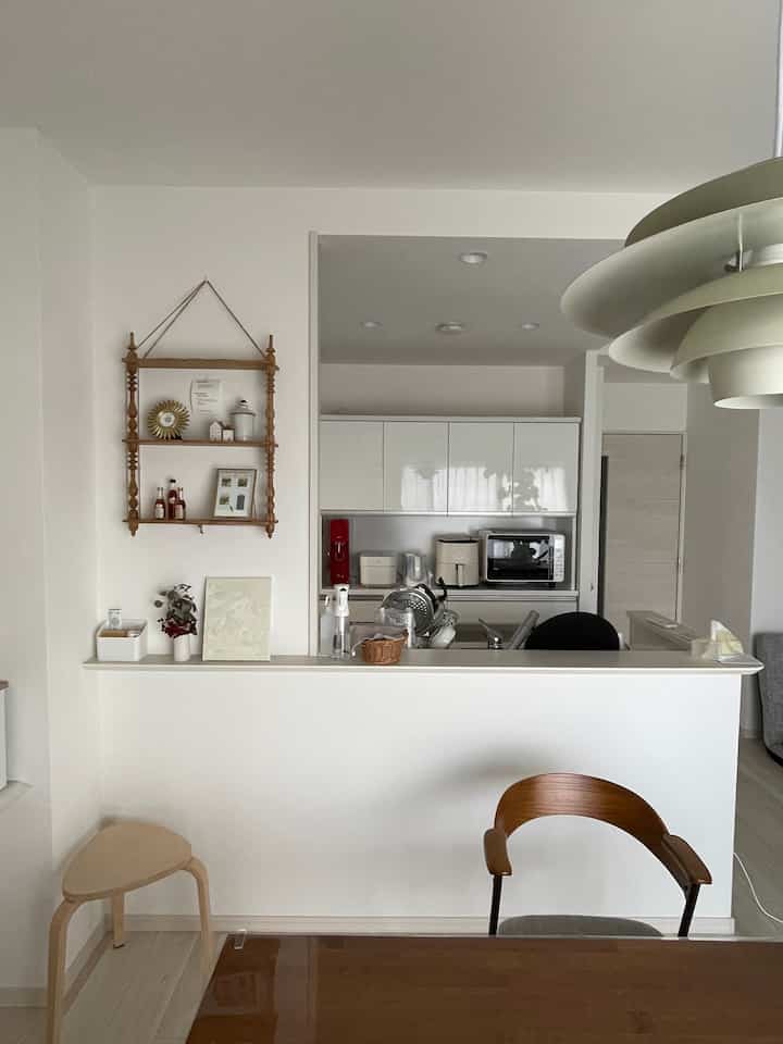 Natural modern dining room with white and brown furniture blending, open kitchen visible in background