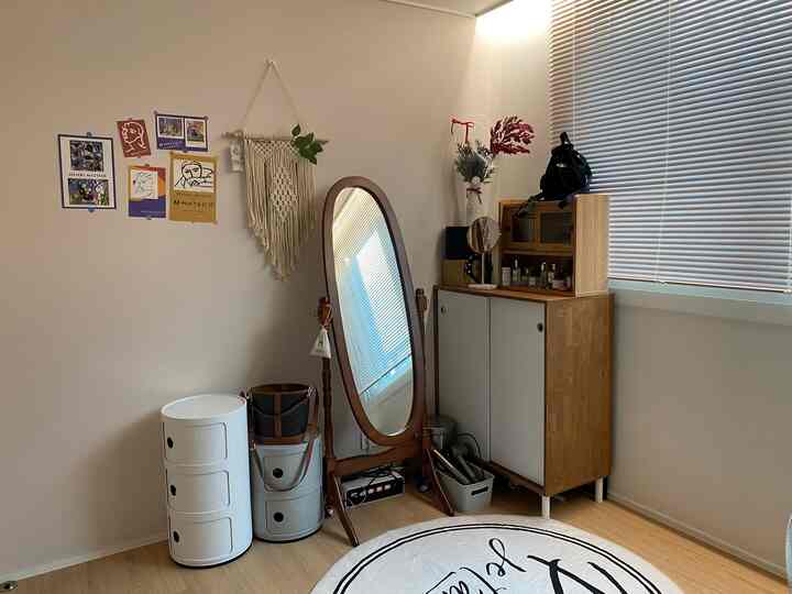 ウッドトーンとホワイトが調和したコンパクトなウォークインクローゼットのコーナー、全身鏡と収納家具が配置された整った空間