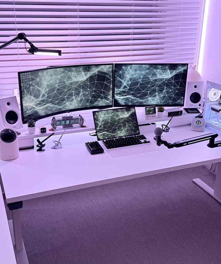 紫色のLED照明が照らす白を基調としたホームオフィスデスク、デュアルモニターとマイクが配置された清潔感ある作業空間