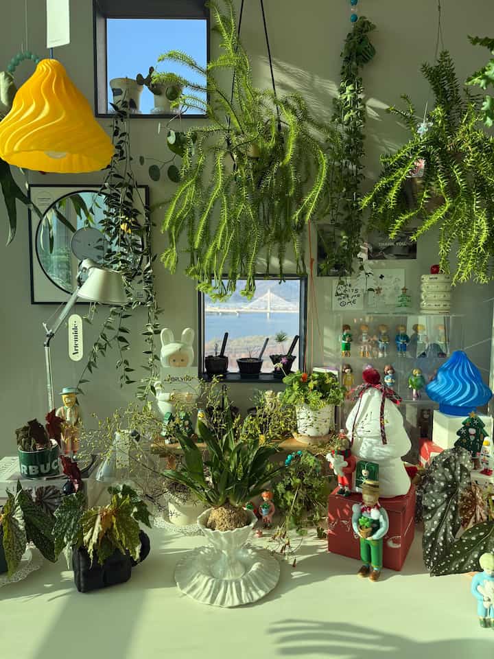 Natural home office space featuring white desk adorned with diverse plants and figures