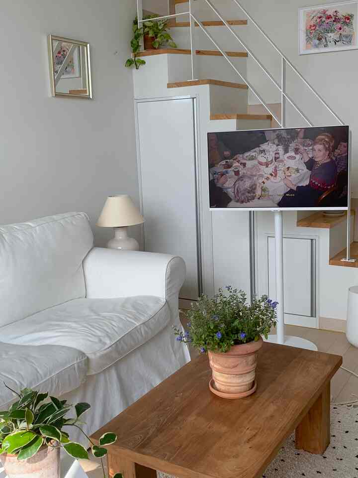 ホワイトとウッドトーンの調和した複層リビング、白いソファと木製コーヒーテーブル、植物が配置されたシンプルな空間