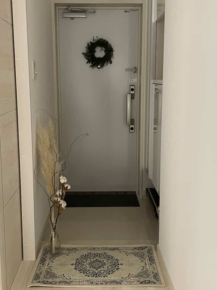 White and natural beige tone entrance featuring an antique mat and dried flower decor creating a cozy atmosphere