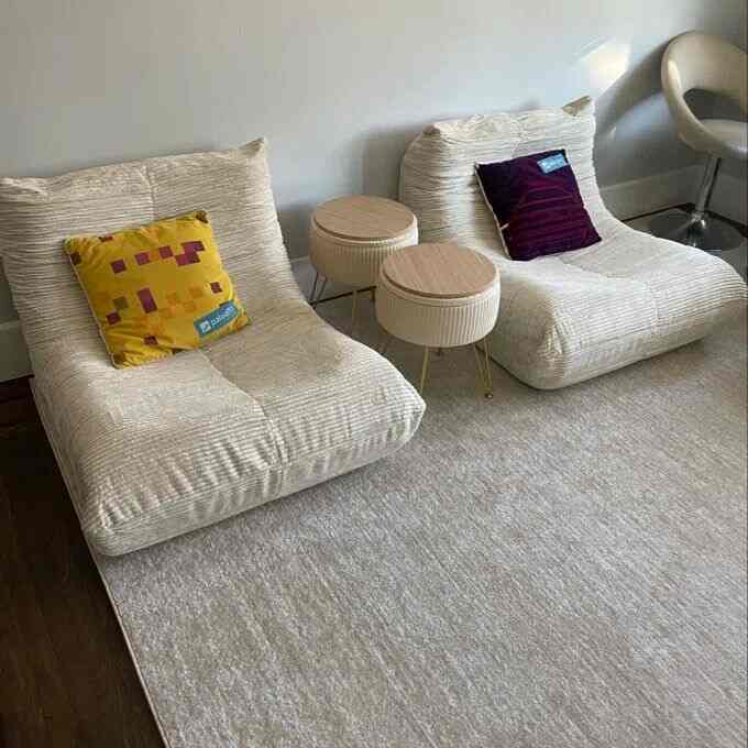 Bright white living room featuring two bean bag lounge chairs and round ottomans creating a comfortable relaxation area