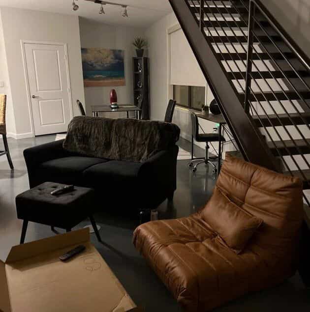 Modern living room in black and brown tones featuring a central black two-seater sofa and brown bean bag-style lounge chair with a sleek atmosphere