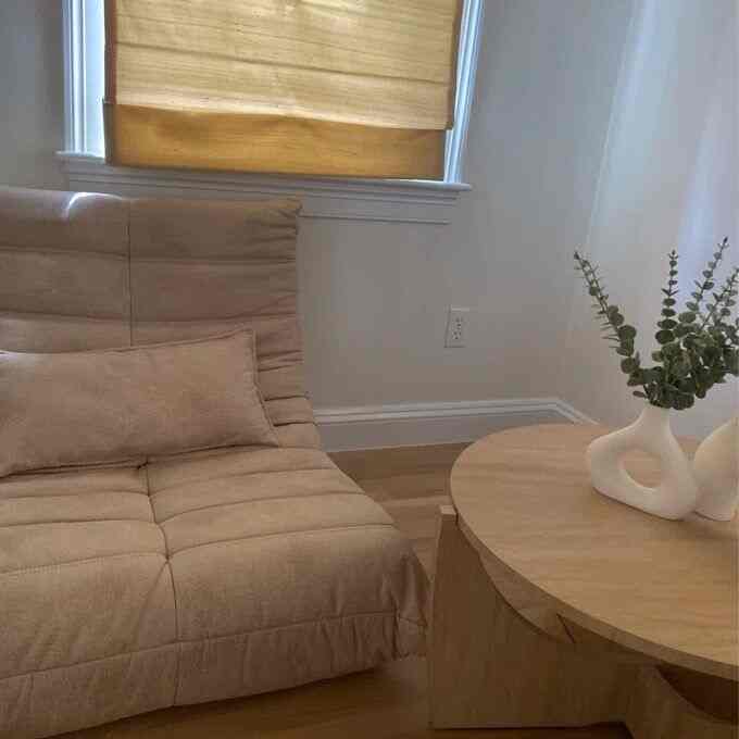 Natural beige and wood tone living room featuring a bean bag chair and round wooden coffee table with a simple and cozy atmosphere