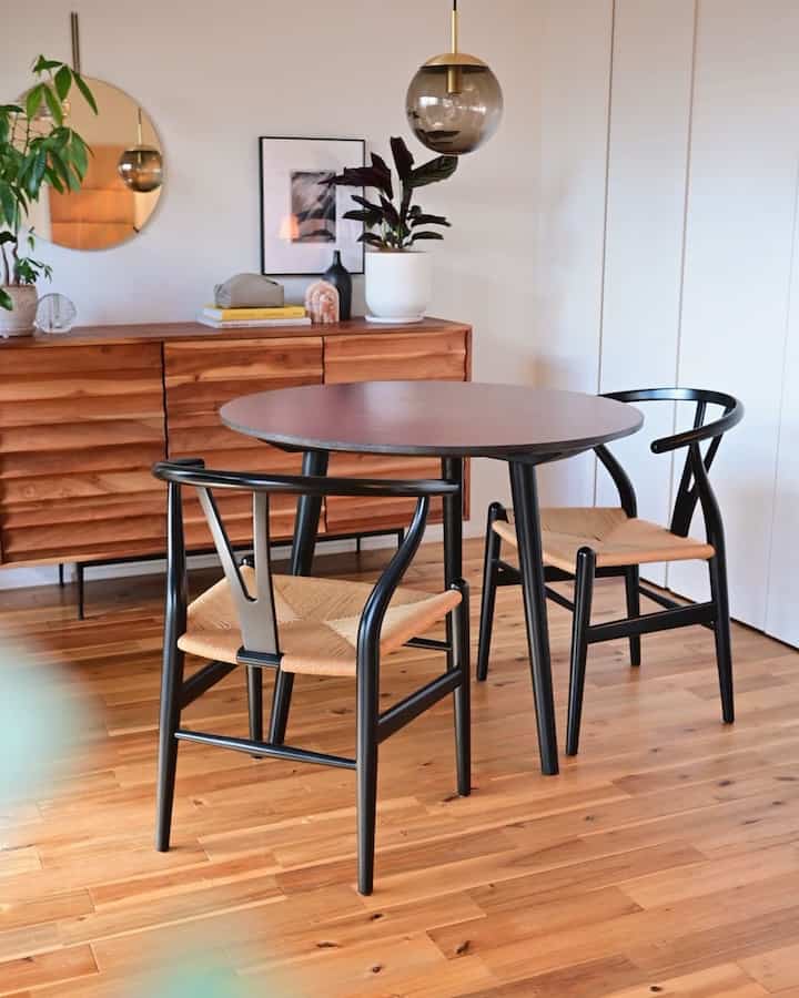 Natural wood tone and black accented dining room featuring Y Chairs and round dining table in a simple cozy setting