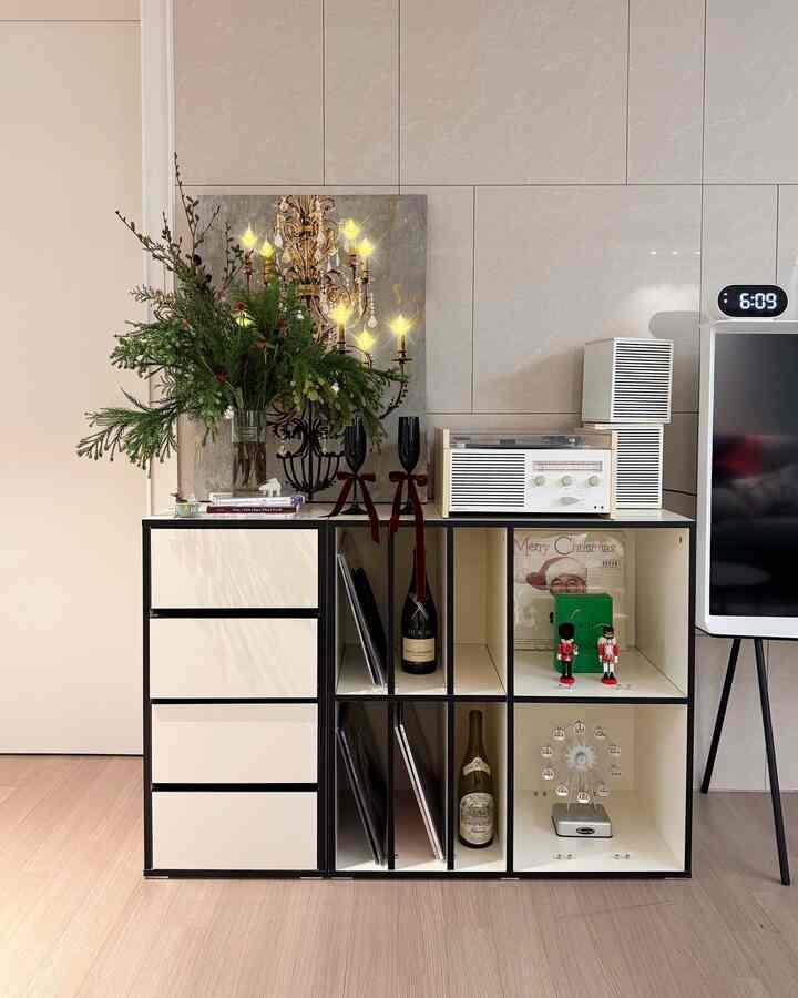 白と木目調のリビング、花瓶とヴィンテージのオブジェが配置された雰囲気のあるインテリア