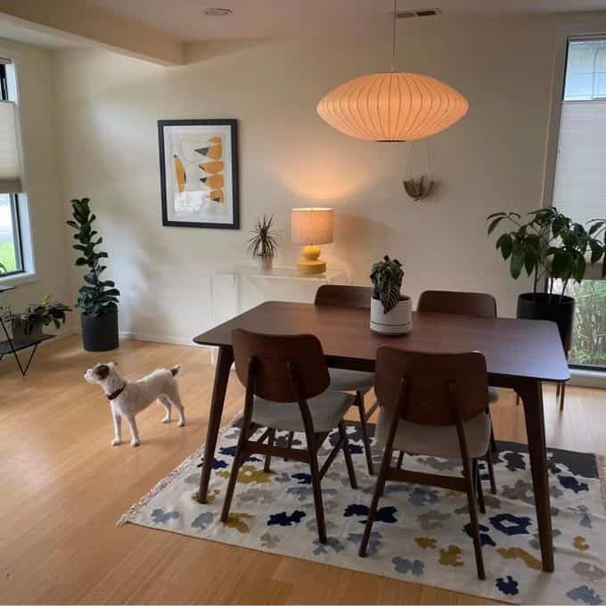 Wood tone floor and dark wood mid-century modern dining table with pendant light in a clean dining room space