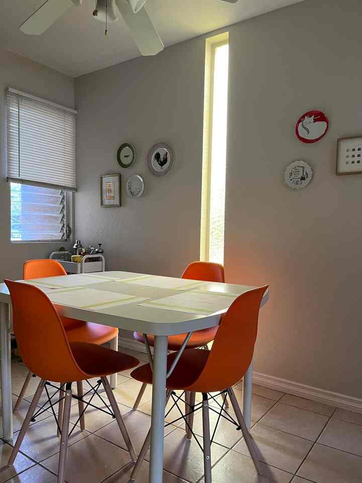Bright white-toned dining room featuring orange mid-century modern dining chairs with a clean and cozy atmosphere