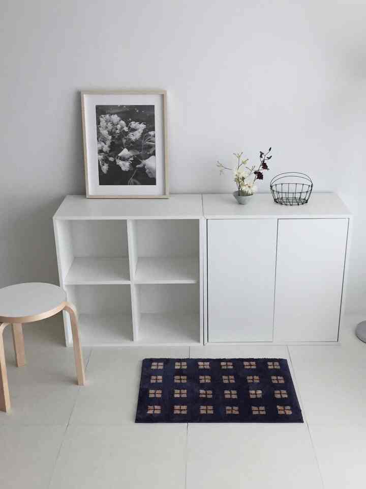 白とネイビーのシンプルなリビングスペース、白いキャビネットとネイビーのドアマットが調和したミニマルなインテリア