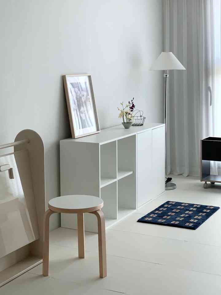 ホワイトとネイビーカラーのコンパクトなリビング、スツールと収納キャビネットが配置されたシンプルな空間