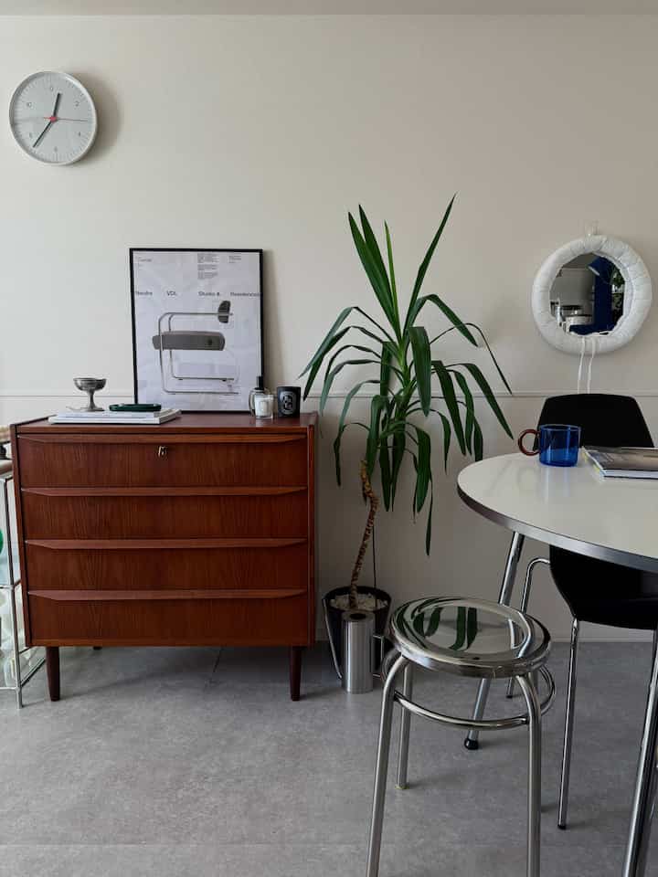 白い壁とラウンドテーブルが配置された、ヴィンテージ北欧家具による洗練されたリビングスペース