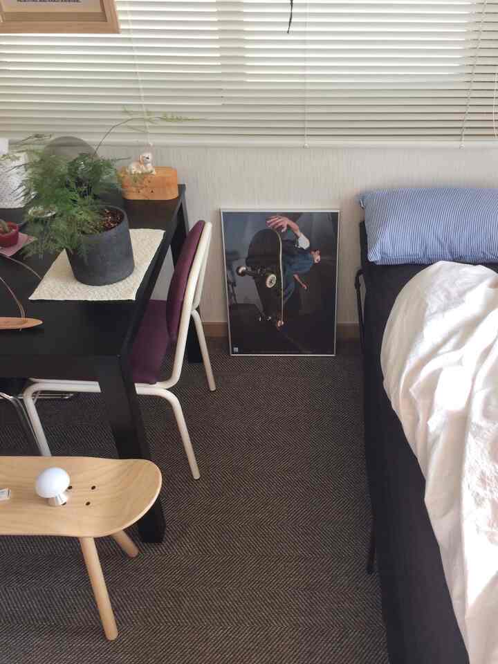 ブラックとホワイトを基調とした寝室、ヘリンボーン柄のラグと木製スケートボードスツール、ダイニングテーブルとチェアが配置されたモダンな雰囲気のインテリア