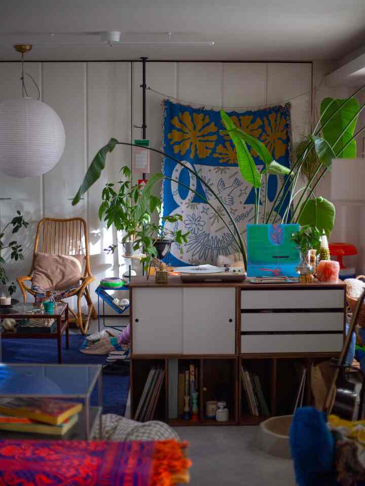 Natural brown-toned living room featuring a storage cabinet and armchair in the center, with various plants creating a warm atmosphere