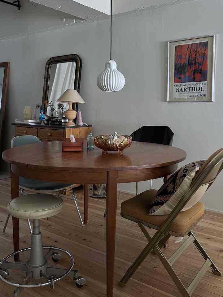 木目調のヴィンテージダイニング、丸いダイニングテーブルと異なる椅子が配された雰囲気のある空間