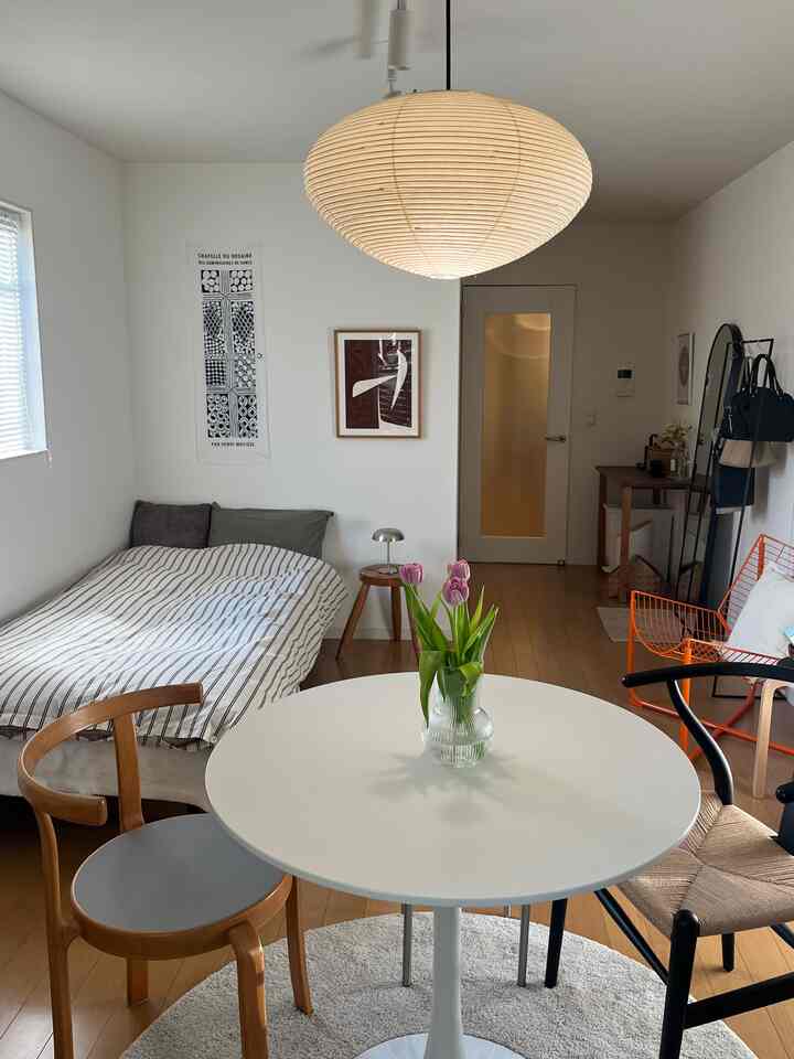 白と木目調が調和する一人暮らしの寝室、ラウンドテーブルとYチェアが配置された自然な雰囲気のインテリア