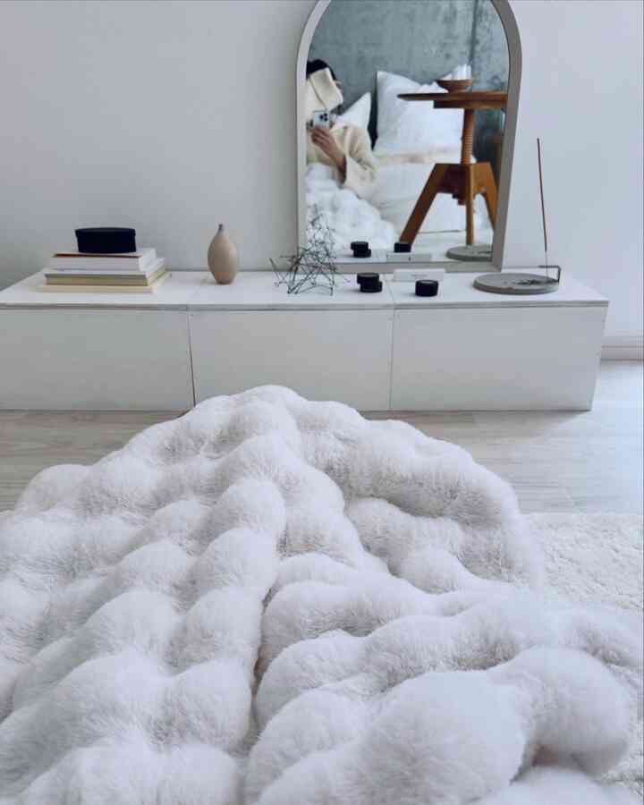 白とナチュラル色調のリビング、アーチ型の大きな鏡と収納棚、柔らかなブランケットが配置された雰囲気のある空間