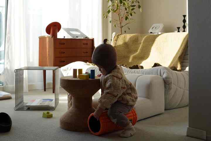 ベージュとホワイトの色調のリビング、ソファや木製収納家具、子供が遊ぶおもちゃがある雰囲気のある空間