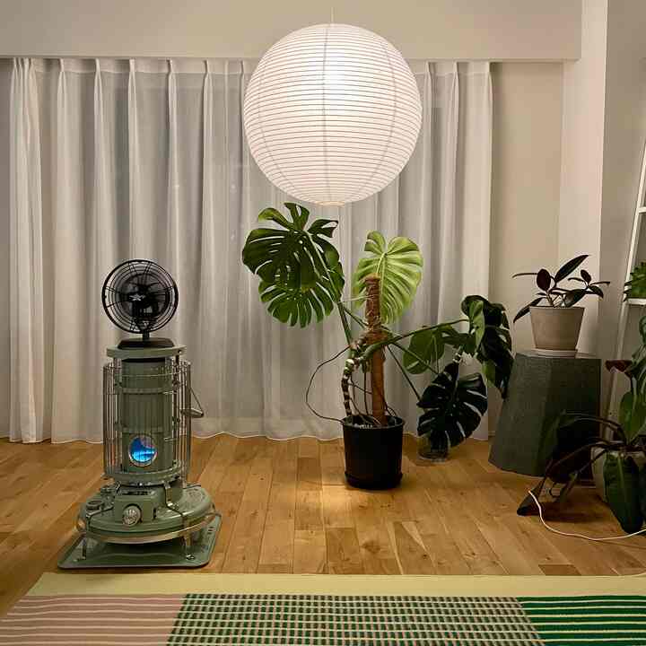 ナチュラルな木目調の床と緑の植物が配置された、明るい紙製ランプシェードのあるリビング空間