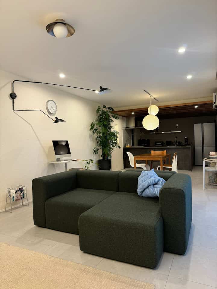 ナチュラルモダンのリビングとダイニング、ダークグリーンのソファと木目調のダイニングテーブルが調和した印象的な空間