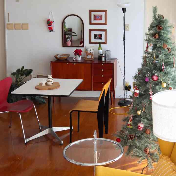 白い壁と茶色の木製家具が配置されたダイニングルーム、クリスマスツリーとサイドテーブルが調和するナチュラルで落ち着いたインテリア