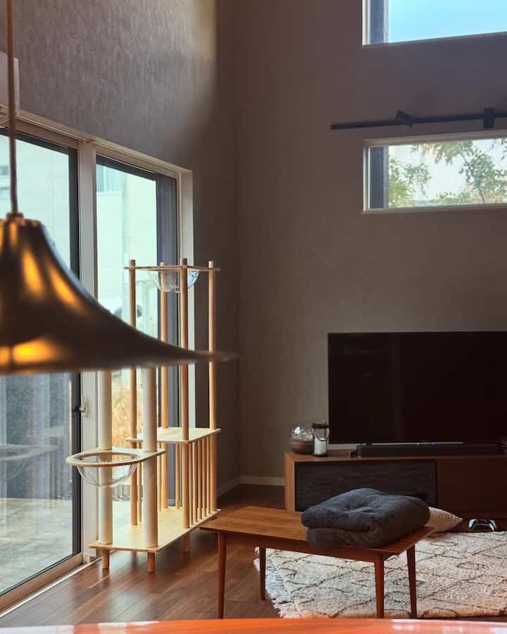 Living room with light brown wood tones and natural colors, featuring a cat tower and TV stand in a cozy setting