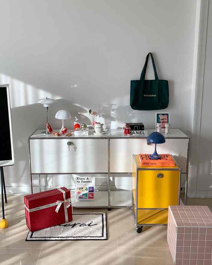 ホワイトとイエローが調和するリビング、USM収納キャビネットとモダンなテーブルランプが配置された雰囲気のあるインテリア