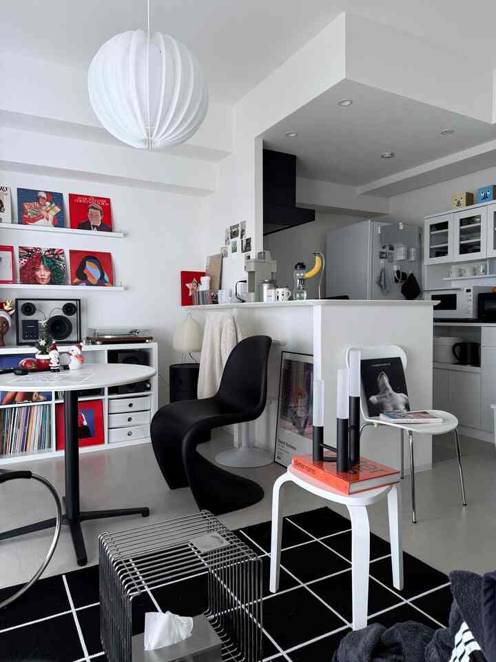 Modern living room in white and black tones featuring stools, coffee table, and pendant light with a clean, stylish atmosphere
