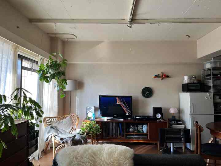 白い壁とブラウンの木製家具、植物とテレビ台が配置されたナチュラルモダンなリビング