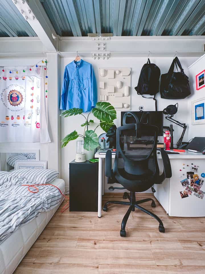 White and black tone studio apartment home office featuring a compact bedroom and office chair with efficient layout