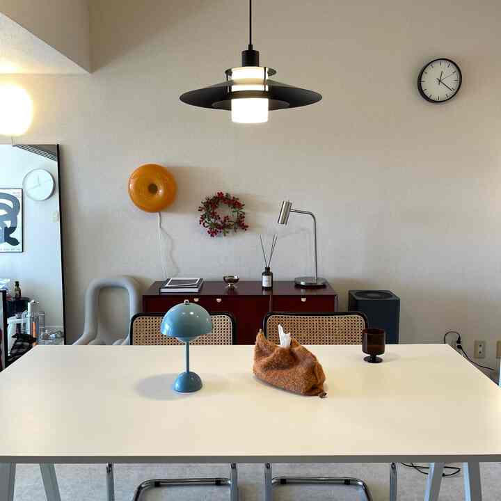 A natural-toned mid-century modern dining space for two featuring a white table and pendant light
