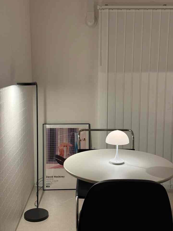 白とダークグレーのトーンのリビング、丸テーブルと間接照明が配置された雰囲気のあるインテリア