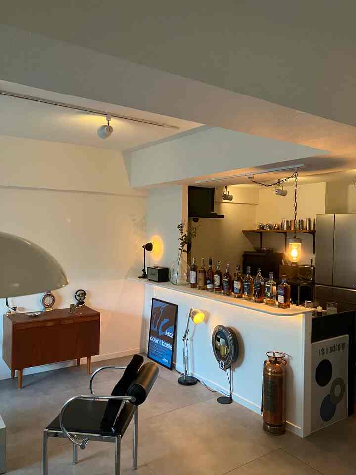 白い壁とブラウンのヴィンテージ家具、インダストリアル要素が調和したミッドセンチュリーモダンな印象的なホームバーのあるリビング